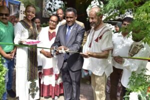 A man in a suit cuts a ribbon at an opening ceremony surrounded by people in traditional Ethiopian attire