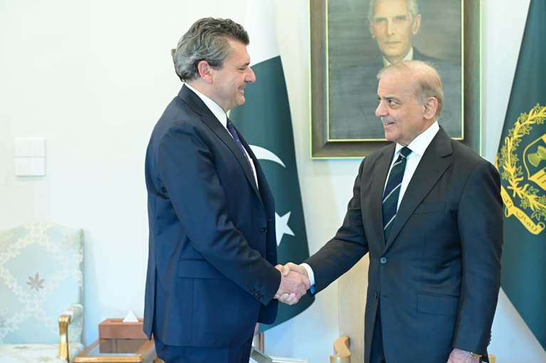 Prime Minister Shehbaz Sharif shaking hands with a foreign official in front of a Pakistani flag