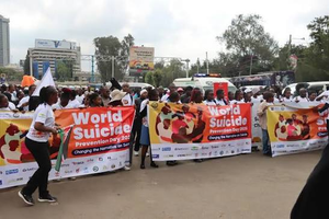 A crowd marches carrying banners reading World Suicide Prevention Day 2024: Changing the Narrative on Suicide