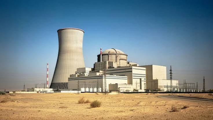 Nuclear power plant facility with a large cooling tower and containment dome in a desert landscape
