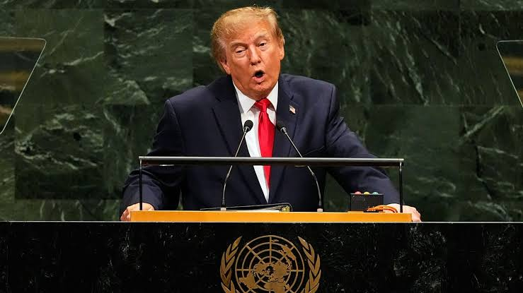 Donald Trump speaking at a podium bearing the United Nations emblem