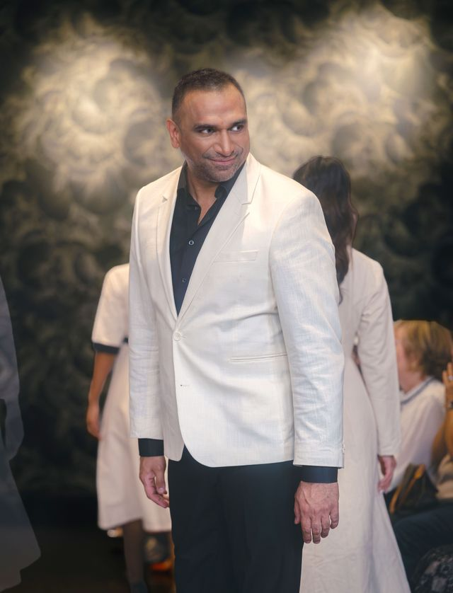 Omar Mansoor wearing a cream-colored blazer and black shirt smiling at an event