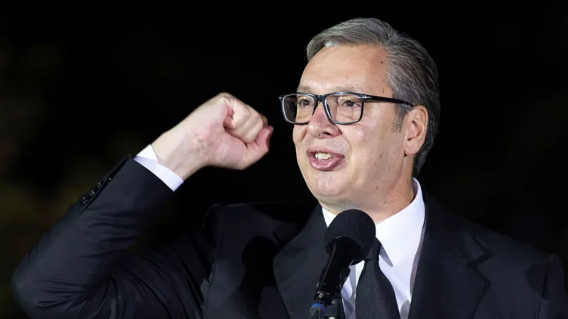 Aleksandar Vučić speaks into a microphone with a raised fist