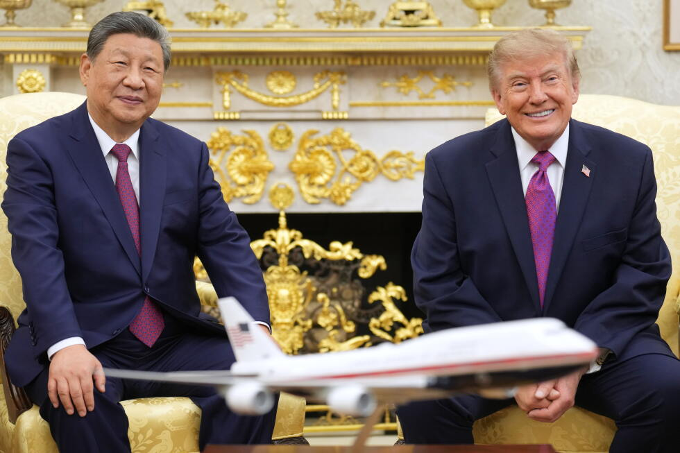 Xi Jinping and Donald Trump seated in ornate chairs, smiling behind a model airplane