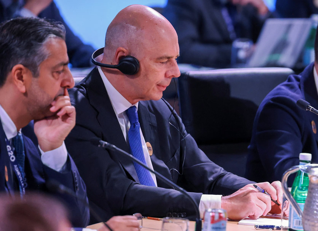 Russian Finance minister Anton Siluanov wearing a translation headset takes notes at a conference table in G20 Conference