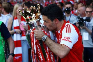 Mikel Arteta kissing the Premier League trophy while wearing an Arsenal jersey