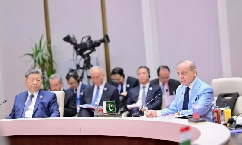 Pakistani Prime Minister Shehbaz Sharif speaks into a microphone as Chinese President Xi Jinping listens at a meeting