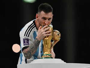 Lionel Messi kisses the FIFA World Cup trophy while wearing an Argentina jersey